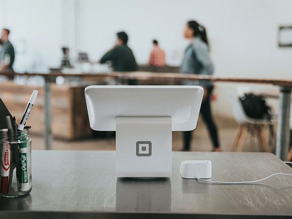 Point of sale terminal on a retail counter with staff working in the background.